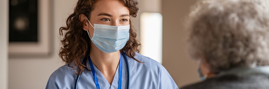 nurse wearing mask talks with patient