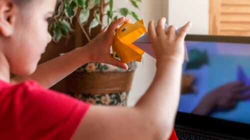 young child shows craft in video call on computer