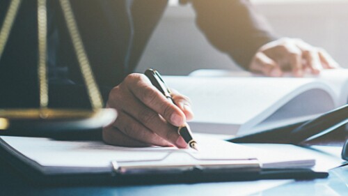 judicial professional reads and takes notes, gavel and scales on desk