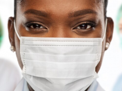 nurses with masks and hairnets look at camera, one in the forefront in focus