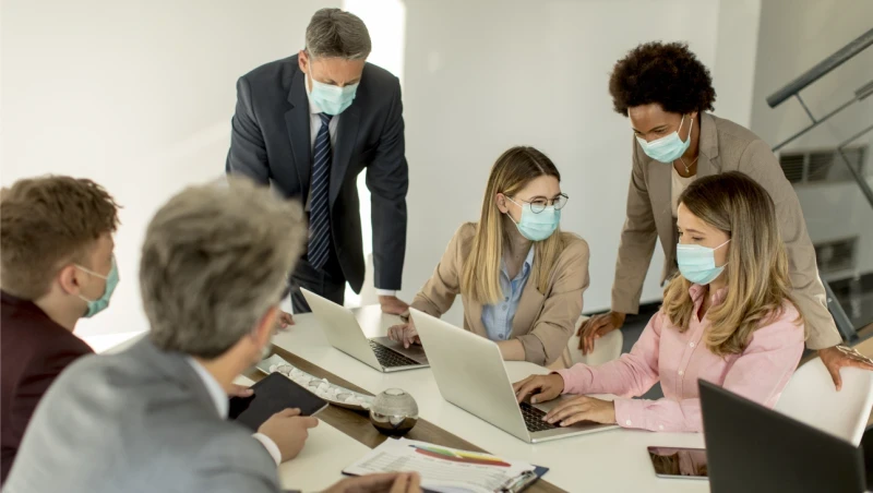 group of people wearing masks in a meeting