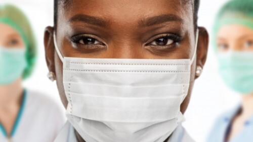 nurses with masks and hairnets look at camera, one in the forefront in focus