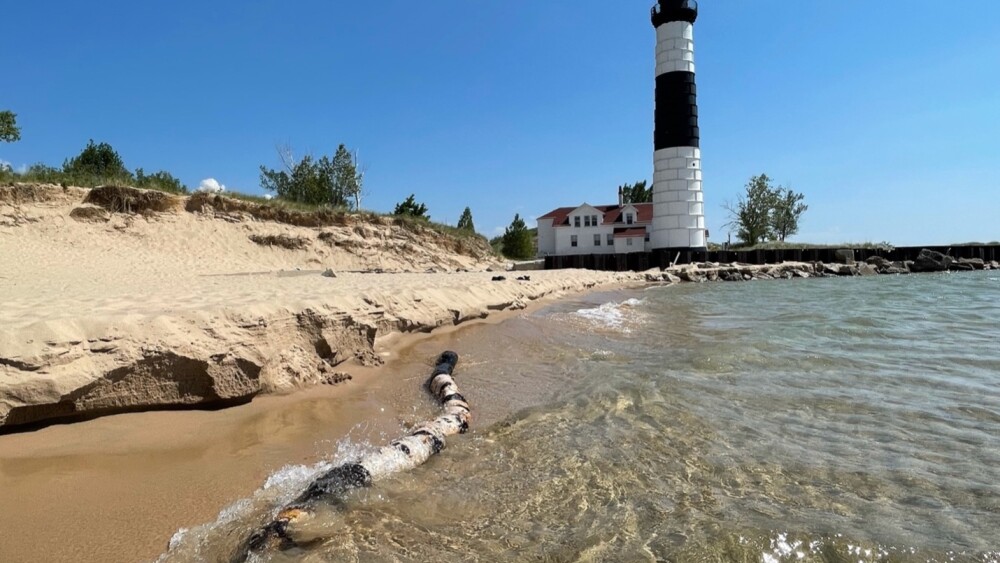 lighthouse along a beach shoreline of clear waters