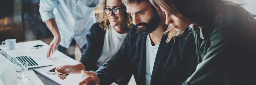 professionals huddle around a laptop