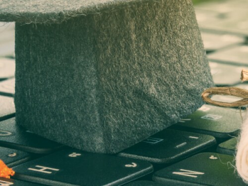 felt graduation cap and diploma resting on a keyboard