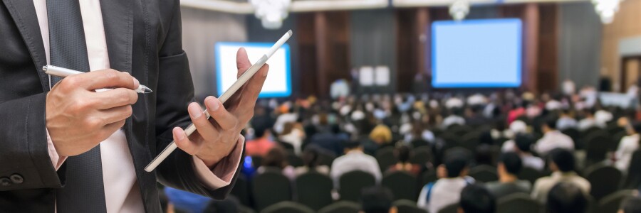 event planner taking notes with a stylus on a tablet at a conference