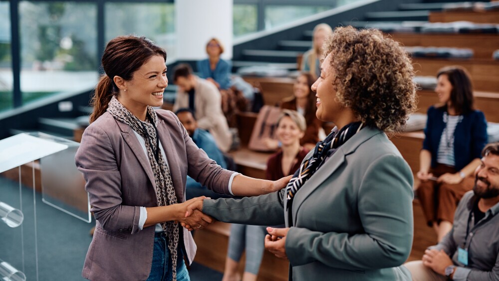 Happy,Female,Entrepreneurs,Shaking,Hands,While,Greeting,During,Business,Seminar