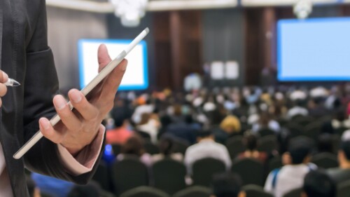 event planner taking notes with a stylus on a tablet at a conference