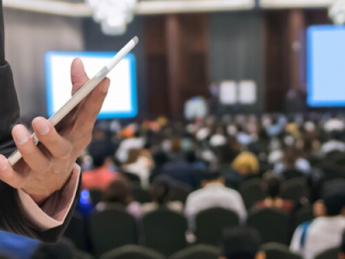 event planner taking notes with a stylus on a tablet at a conference