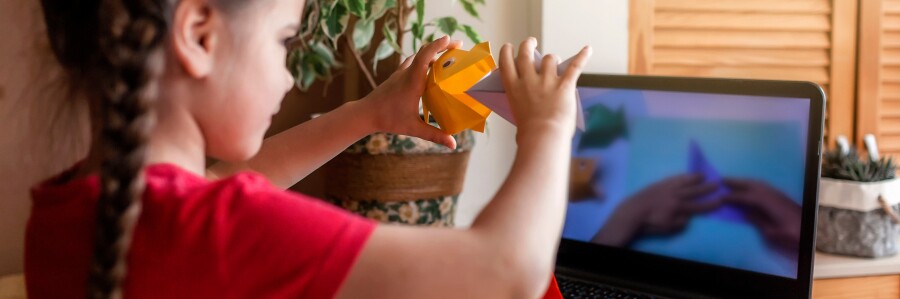 young child shows craft in video call on computer