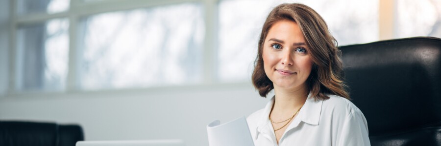 professional in a conference room holding a report and smiling