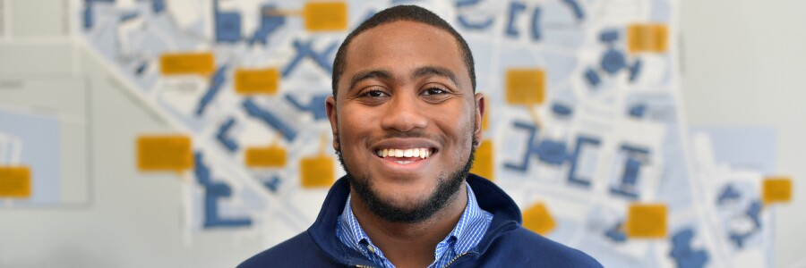 young black man standing in front of a map of Kent State University's campus