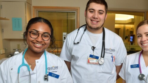 nursing students wearing stethoscopes smile in hospital room