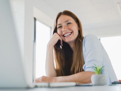 Happy,Young,Caucasian,Woman,Working,On,Laptop,Laughing,At,Office