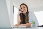 Happy,Young,Caucasian,Woman,Working,On,Laptop,Laughing,At,Office