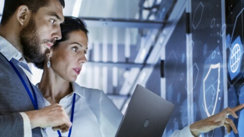 tech professionals working on large digital screen with abstract images