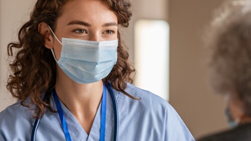 nurse wearing mask talks with patient