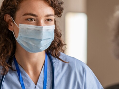 nurse wearing mask talks with patient