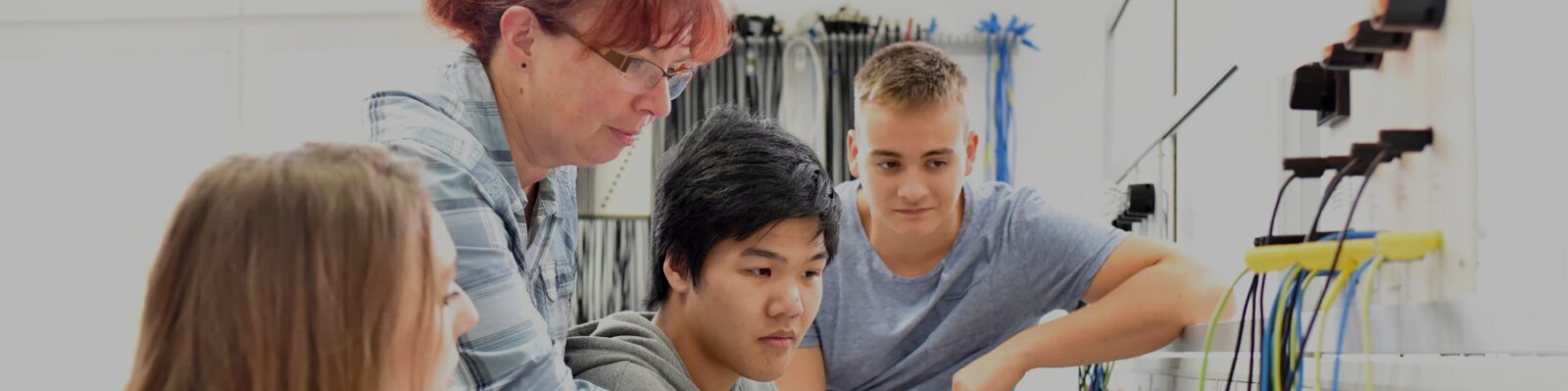 group of technical students with educator looking at computer hardware