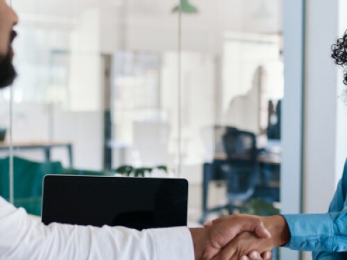 two professionals shake hands in an office