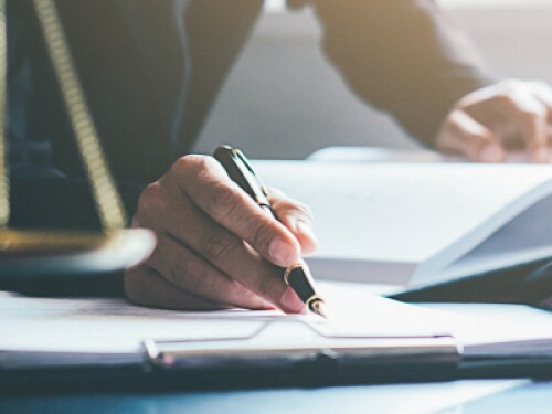 judicial professional reads and takes notes, gavel and scales on desk