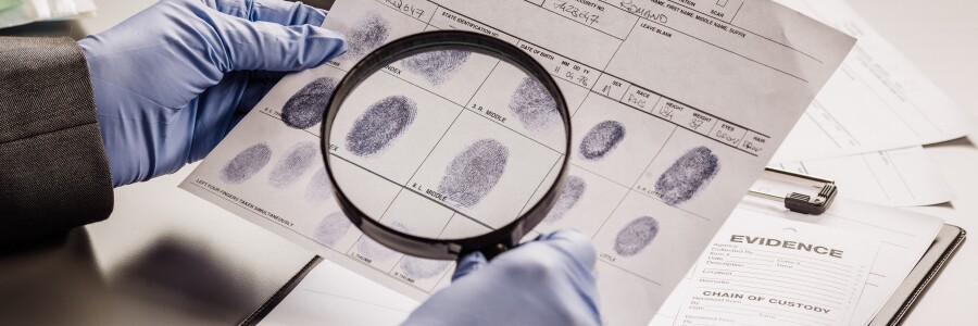 investigator examines fingerprints with magnifying glass