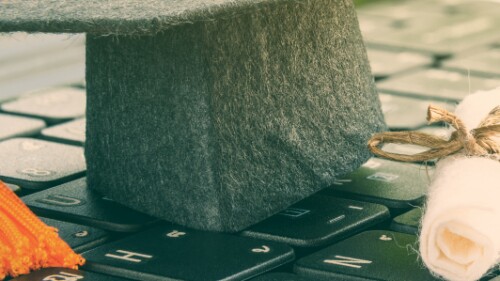 felt graduation cap and diploma resting on a keyboard