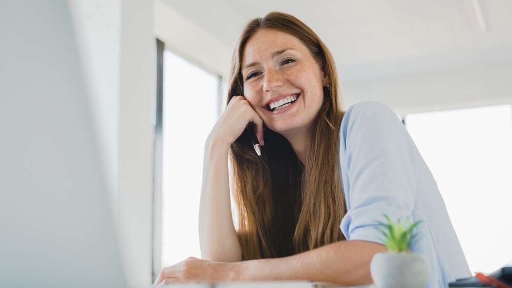 Happy,Young,Caucasian,Woman,Working,On,Laptop,Laughing,At,Office
