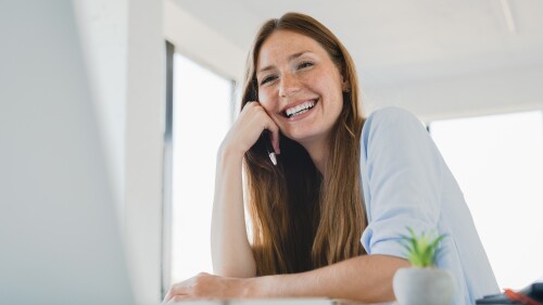 Happy,Young,Caucasian,Woman,Working,On,Laptop,Laughing,At,Office