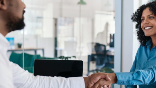 two professionals shake hands in an office